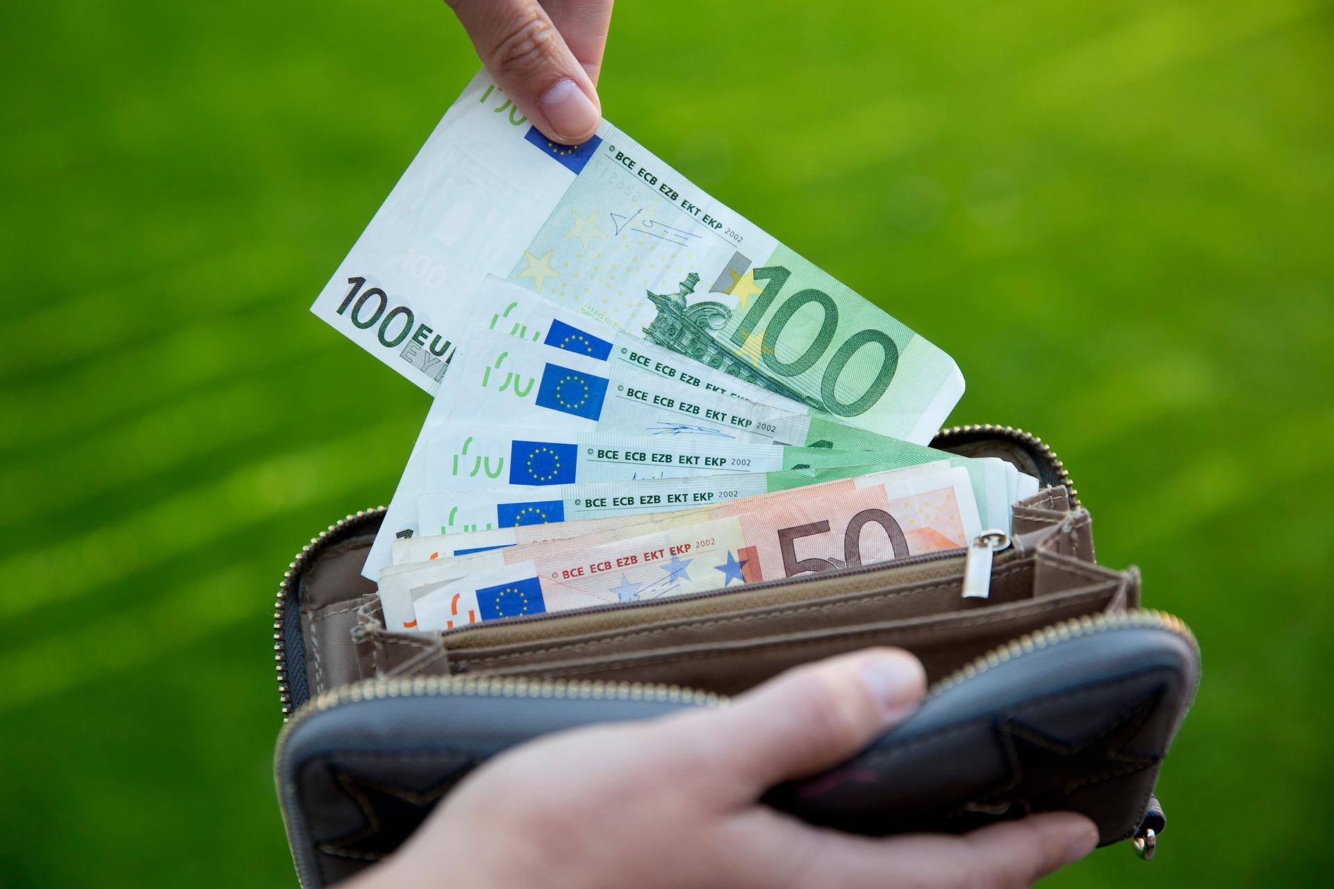 hand die een 100-euro bankbiljet uit een portemonnee pakt