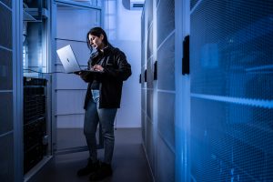 Foto van persoon met laptop in serverruimte