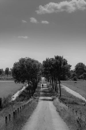 Zwart-wit foto van landweg richting horizon met halverwege fietser